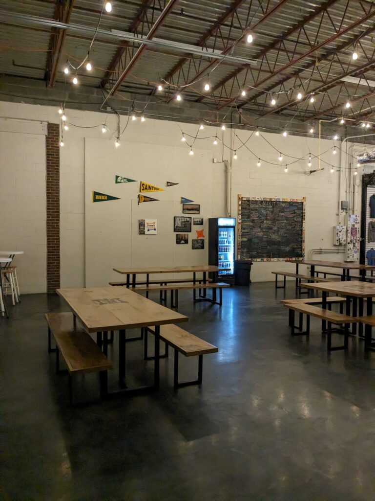 Seating in tap room with The Beer It Forward board.