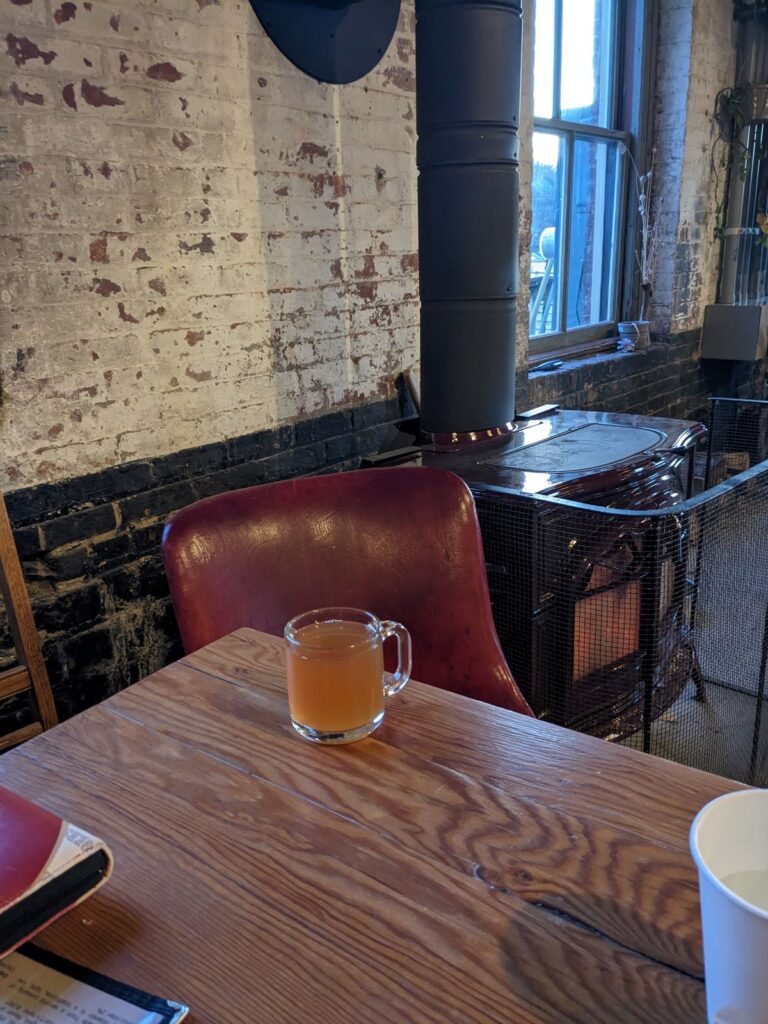 Inside seating near the fire with a mug of cider.