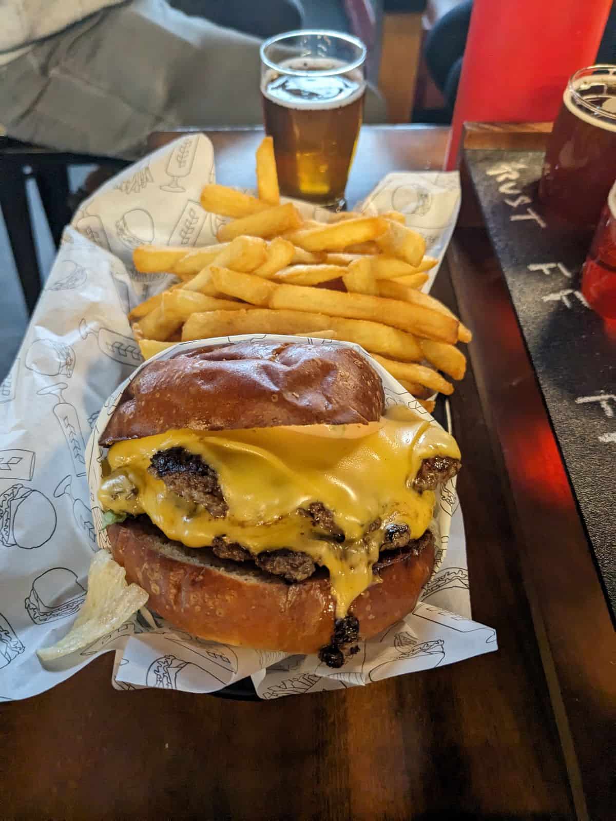 Cheeseburger and french fries in a basket on a table.