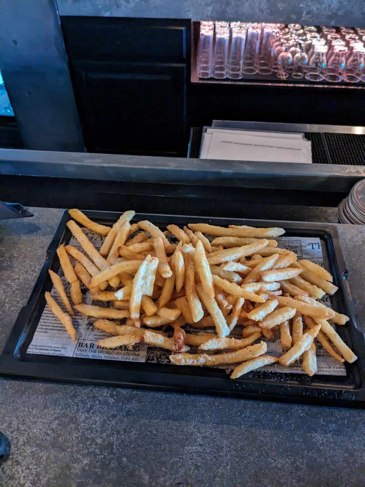 A tray full of french fries on the bar.